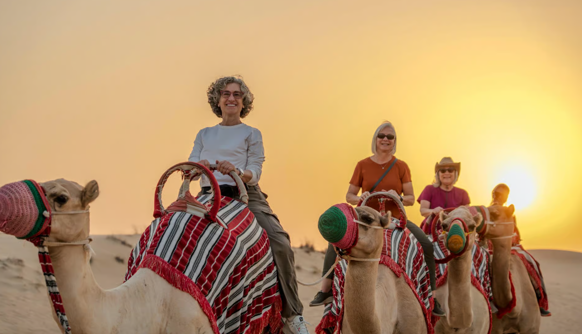 Family camel tour in the desert at sunset
