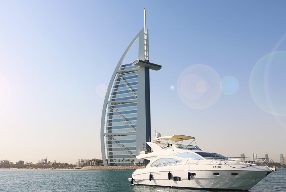 White luxury yacht on Dubai water in front of Burj Al Arab